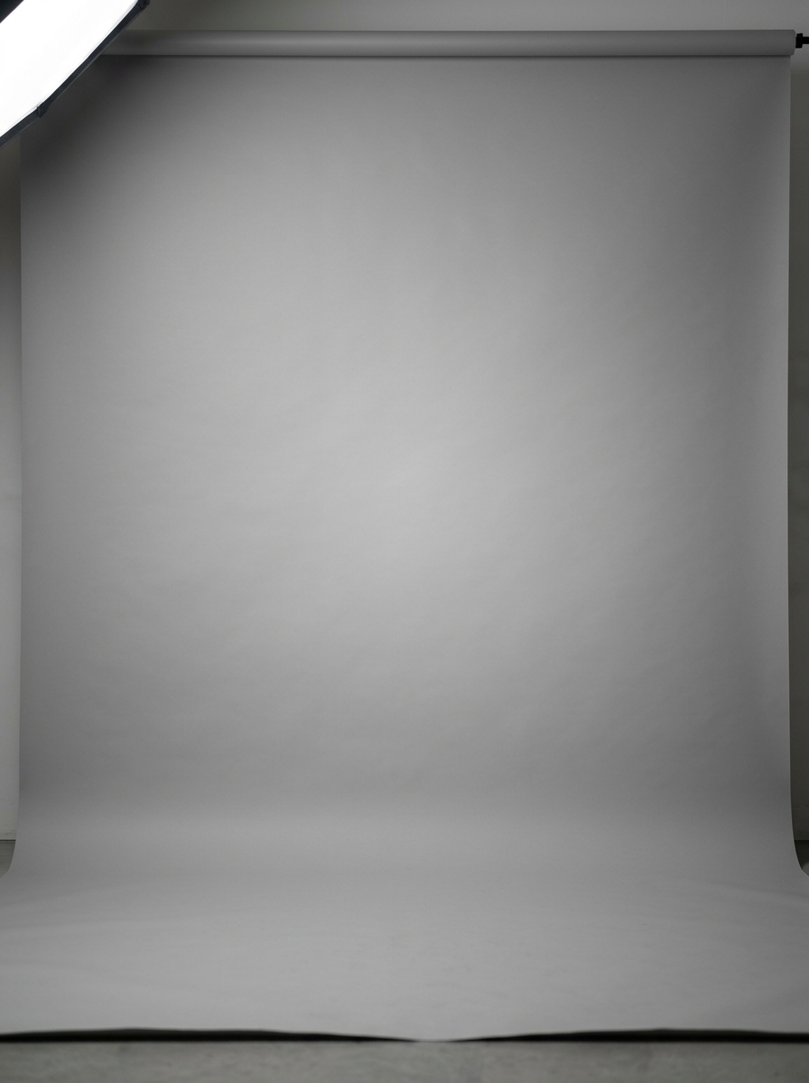Calibrated neutral grey studio paper roll with gentle center key light falloff for corporate headshots